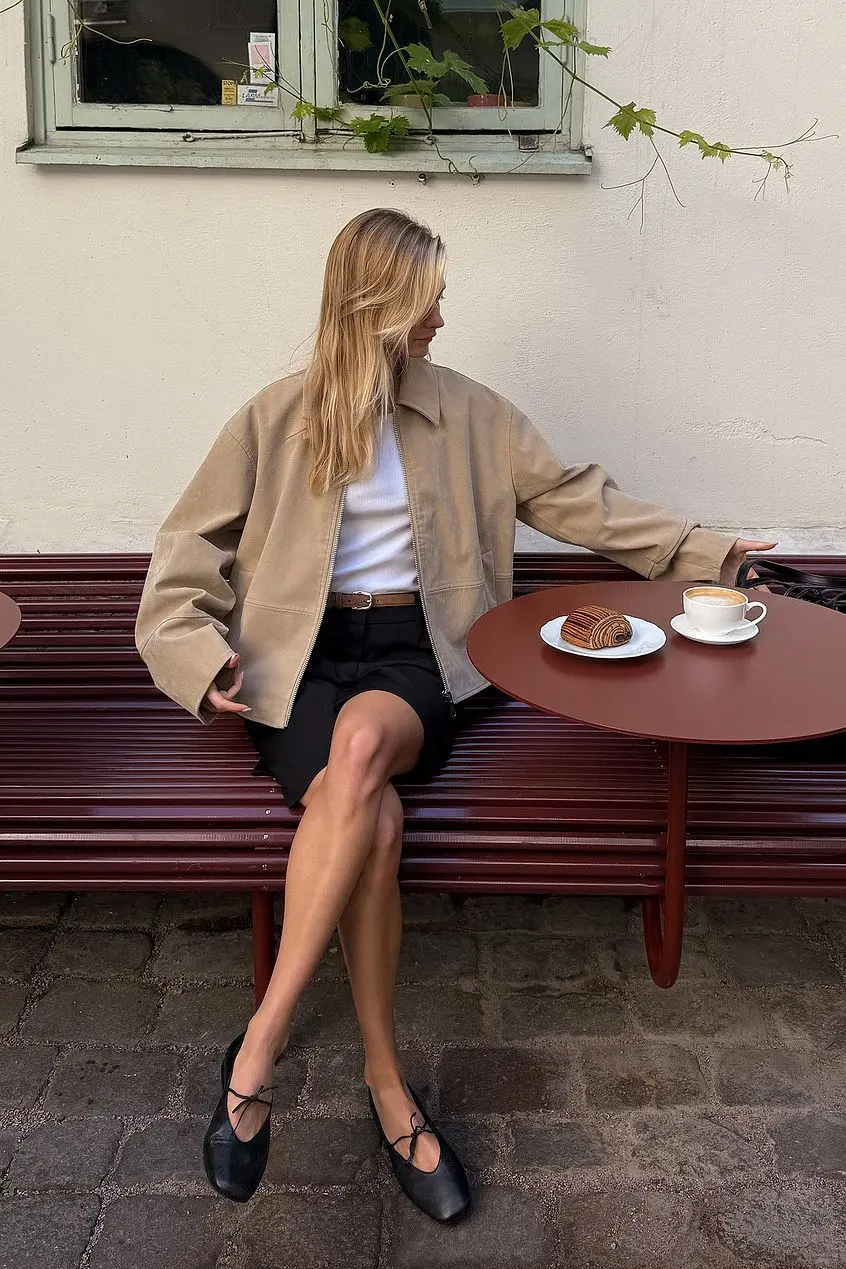 Minimalist spring outfit featuring tan leather jacket with black shorts
