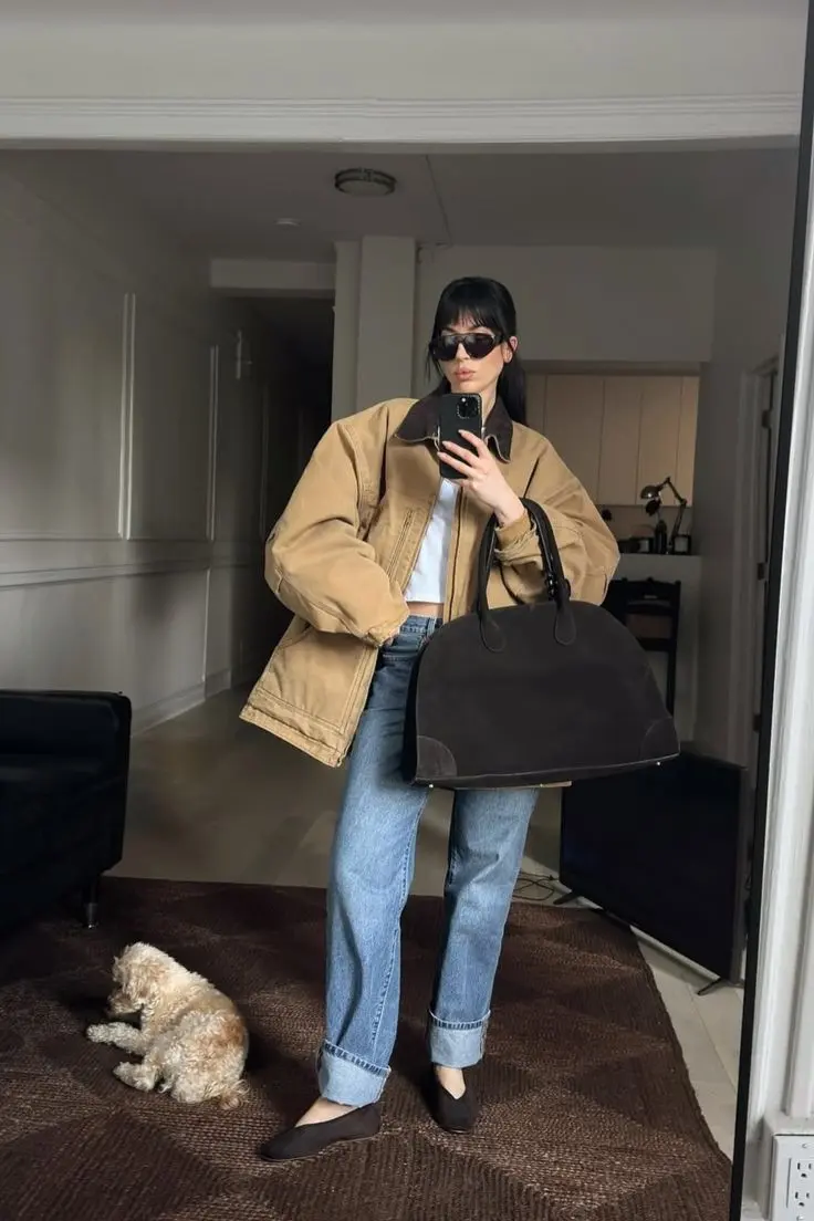 Oversized beige barn jacket styled with white crop top and straight-leg jeans for minimalist spring look