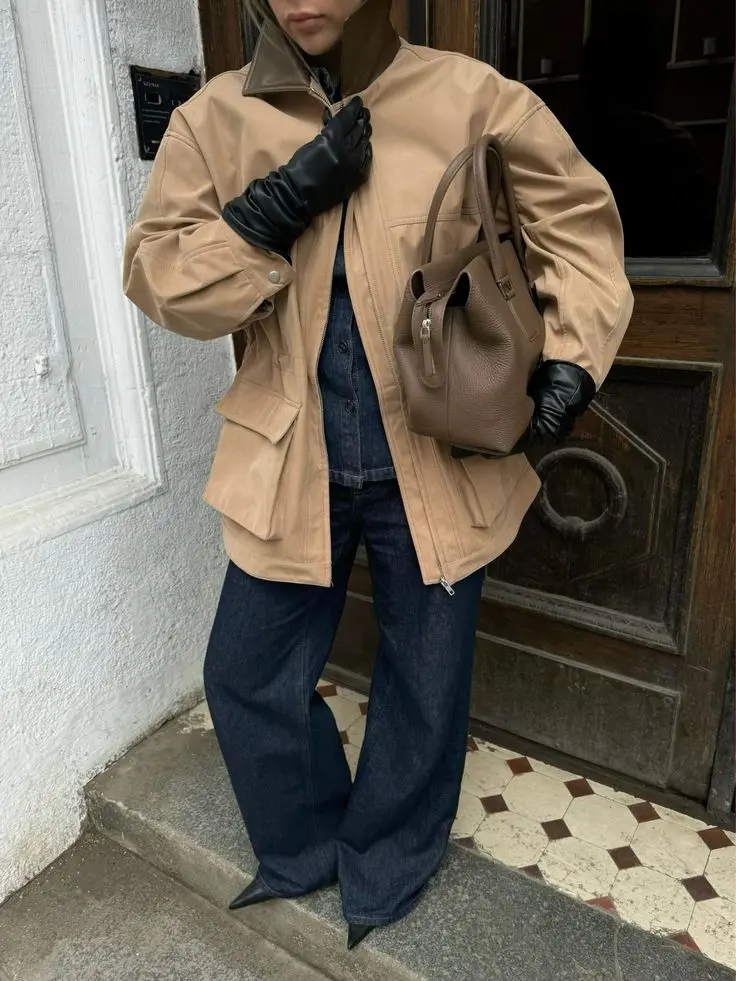 Tan barn jacket paired with indigo wide-leg jeans and leather accessories for elevated spring street style