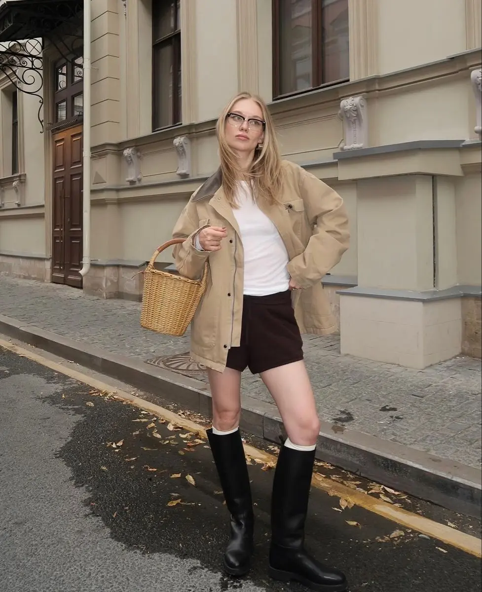 Barn jacket spring outfit with brown shorts, white tee, riding boots, and wicker basket bag