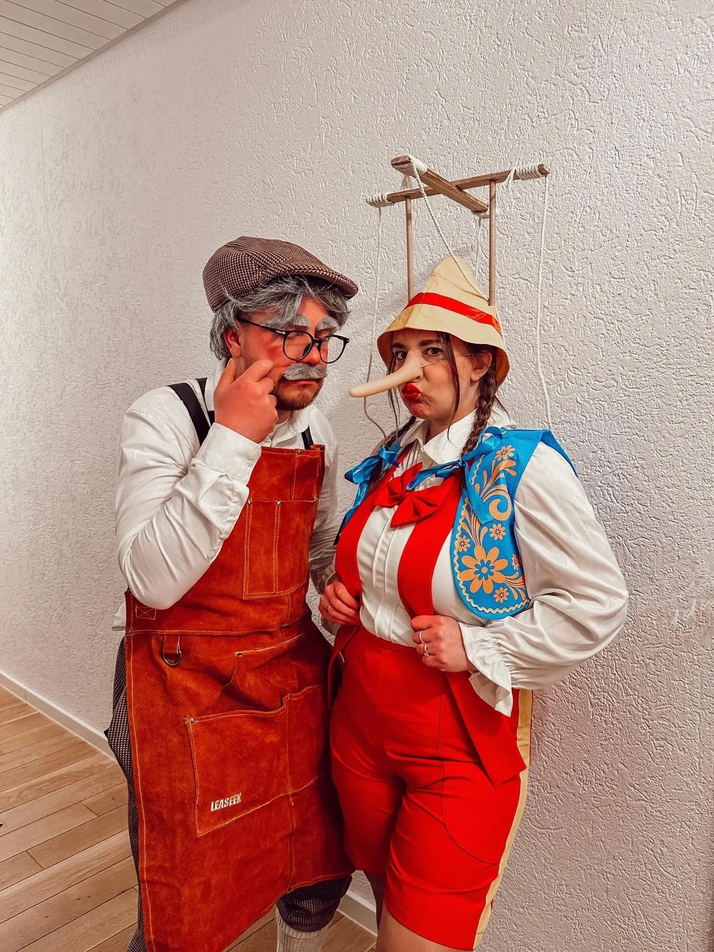 Man in leather apron and glasses as Geppetto, woman in lederhosen with puppet strings as Pinocchio costume 7
