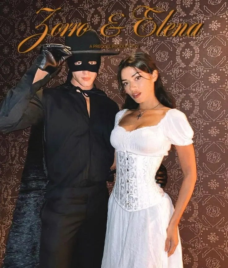 man in black outfit with mask next to woman in white corset dress with black accessories outfit 4