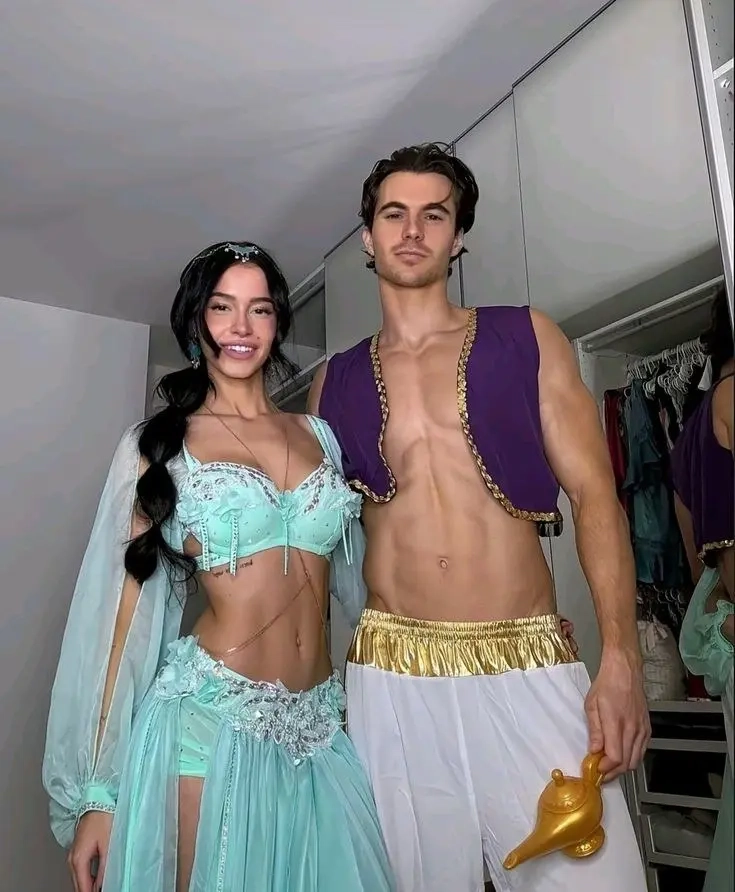 woman in turquoise belly dance costume with jewelry next to shirtless man in purple vest and white pants with gold lamp outfit 16