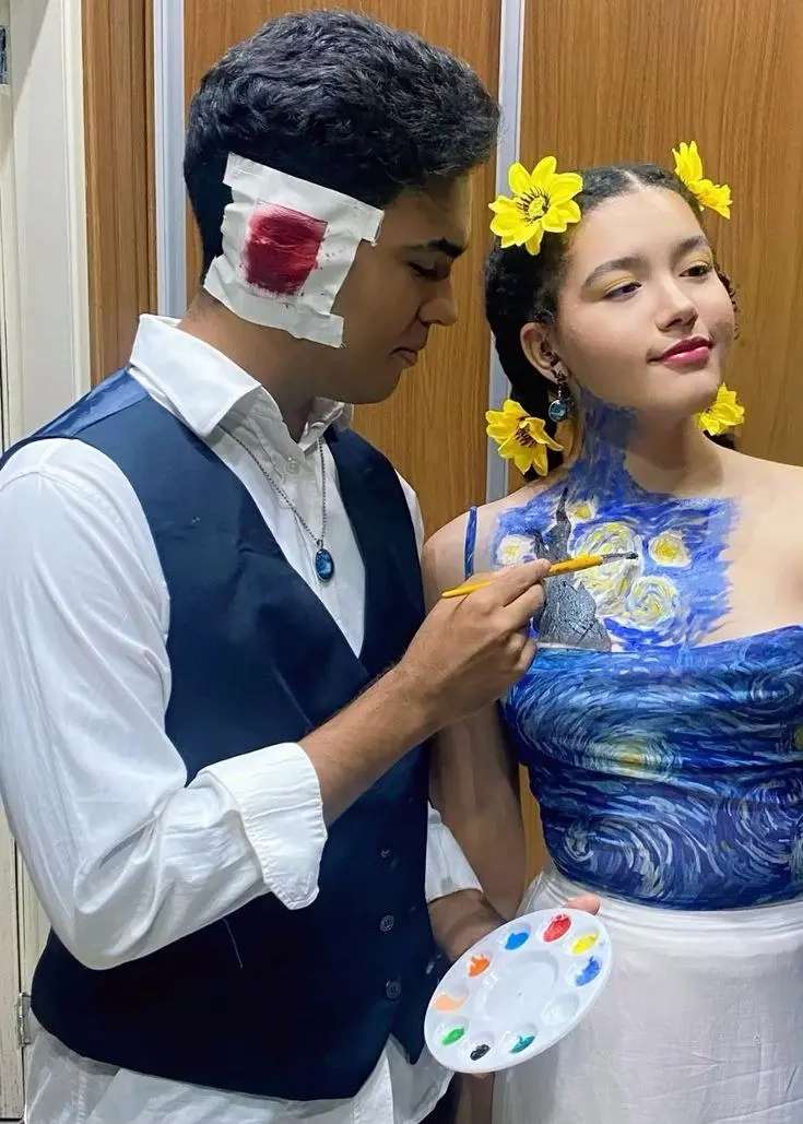man in vest and white shirt with bandaged ear next to woman in blue dress painted with starry night pattern and sunflowers in hair outfit 6