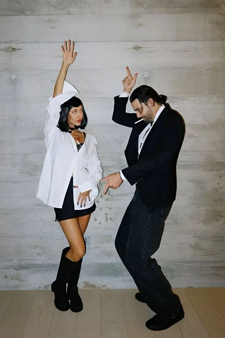woman in white shirt and black outfit with black bob wig next to man in black suit doing dance moves outfit 10