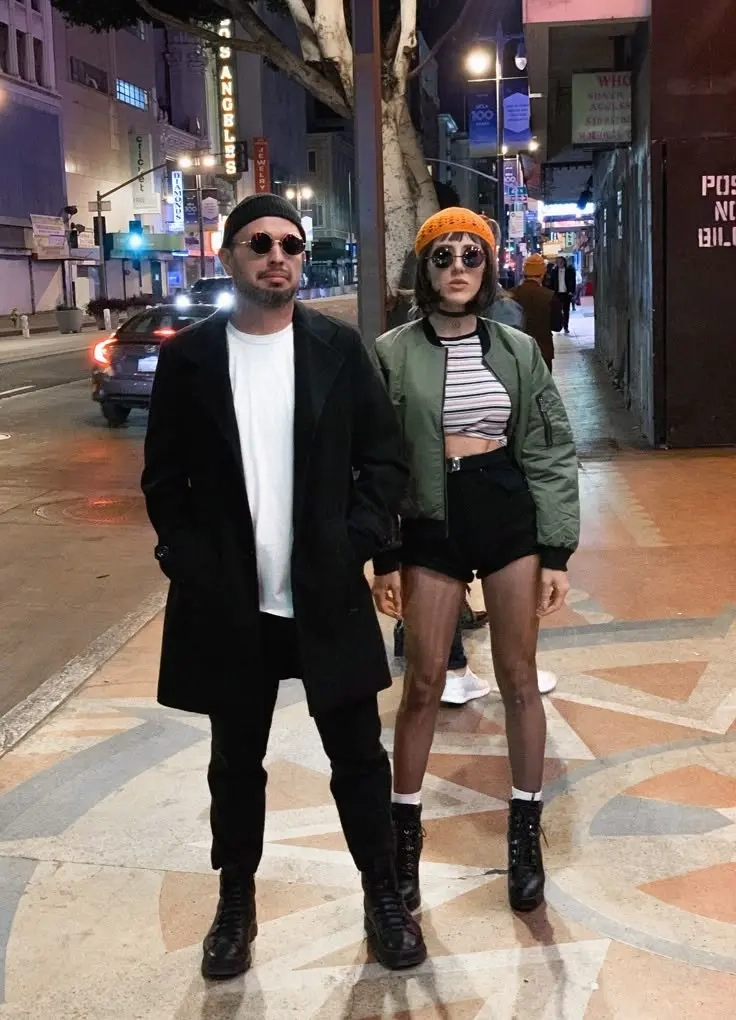 man in black coat and beanie with sunglasses next to woman in green bomber jacket and orange beanie walking on street outfit 11