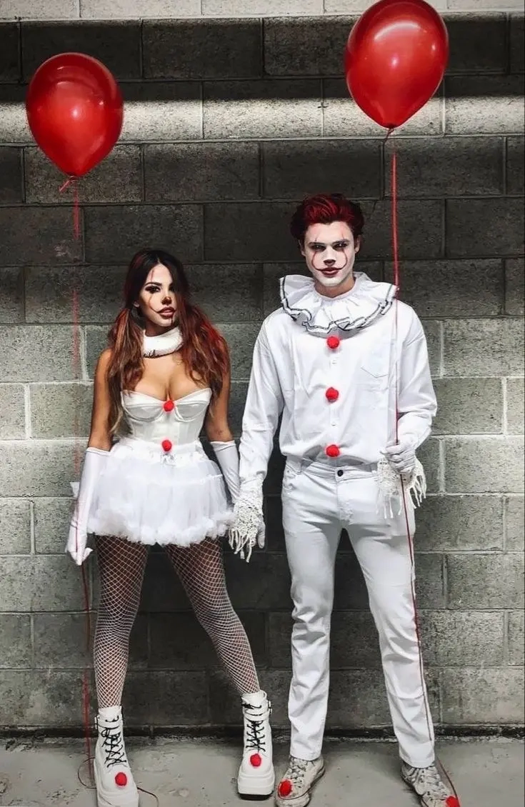 woman in white corset dress with red accents next to man in white clown costume with red nose and face paint outfit 18