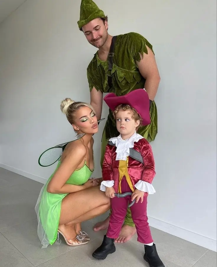 woman in tinkerbell costume green dress with wings, man in peter pan costume green tunic, child in captain hook costume red coat peter pan family outfits 4