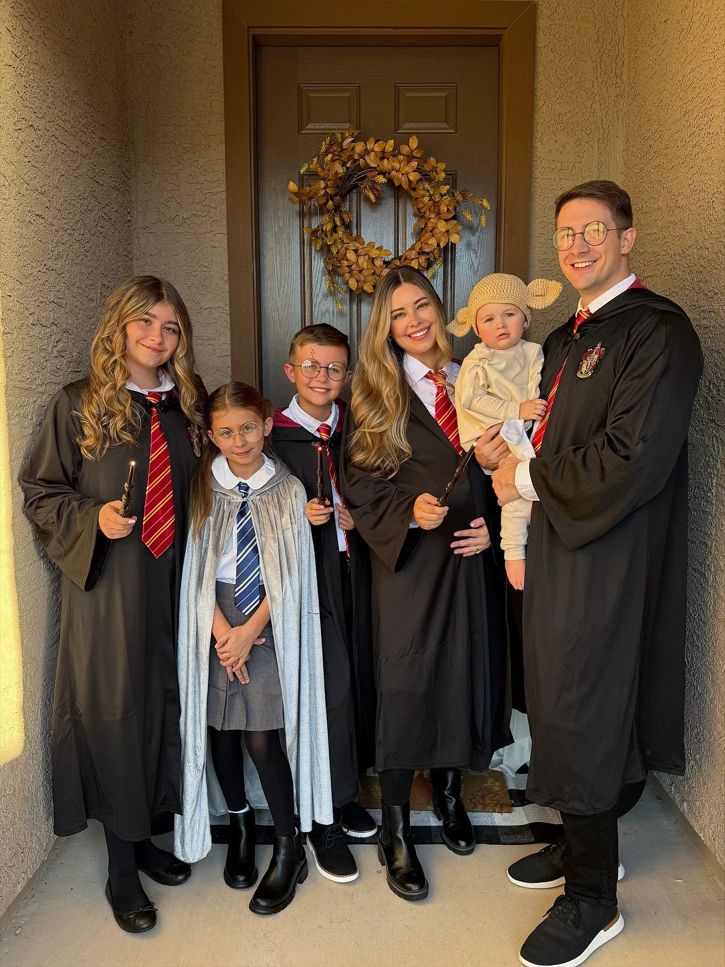 family in hogwarts robes with house ties gryffindor hufflepuff, children and adults with wands glasses, baby in dobby costume harry potter family outfits 8