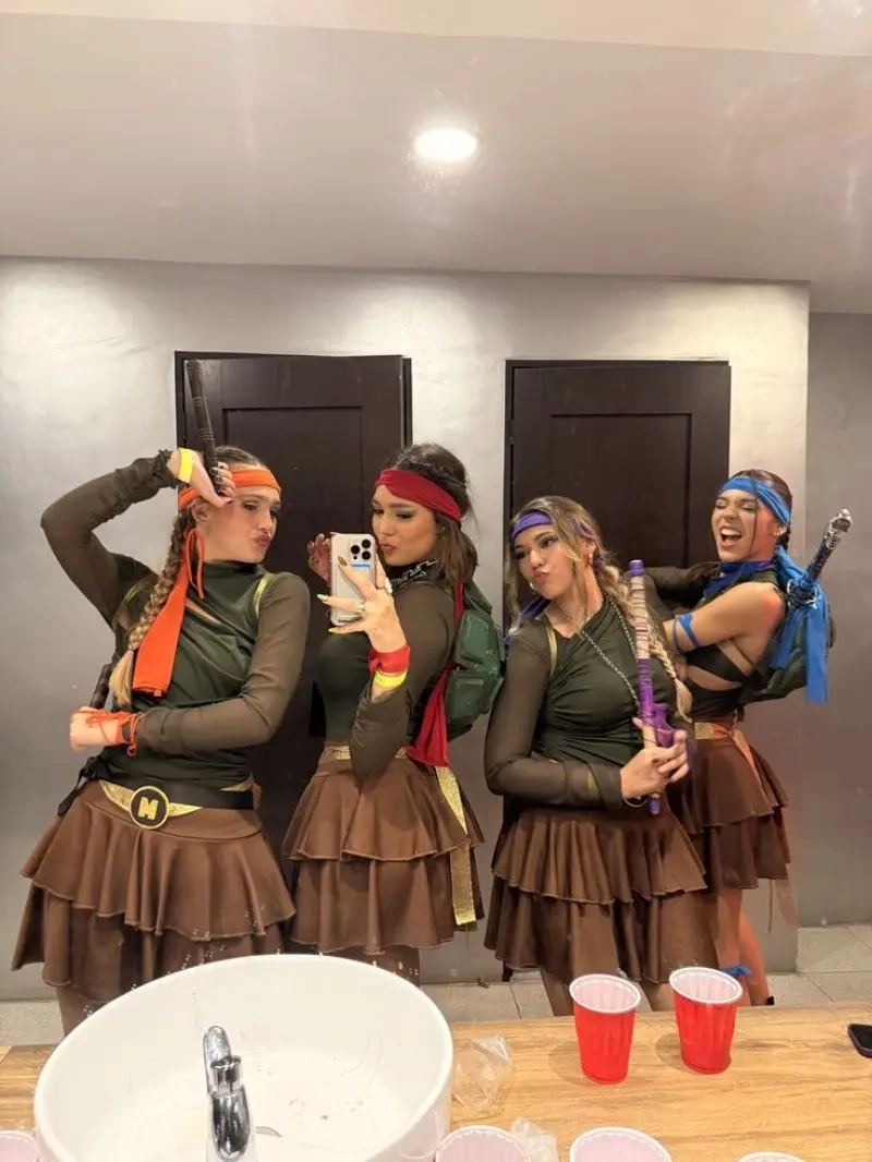 four women in ninja turtle costumes with colored headbands brown tops and weapons outfit 2