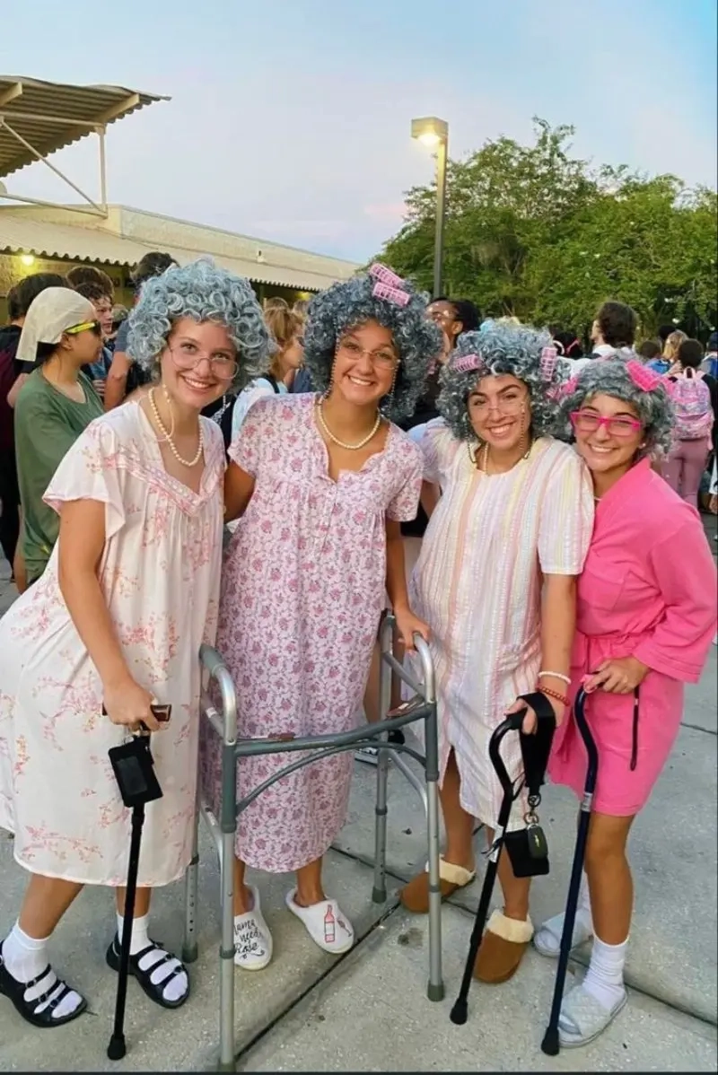 young women dressed as elderly ladies with gray wigs floral dresses glasses and walker props outfit 10