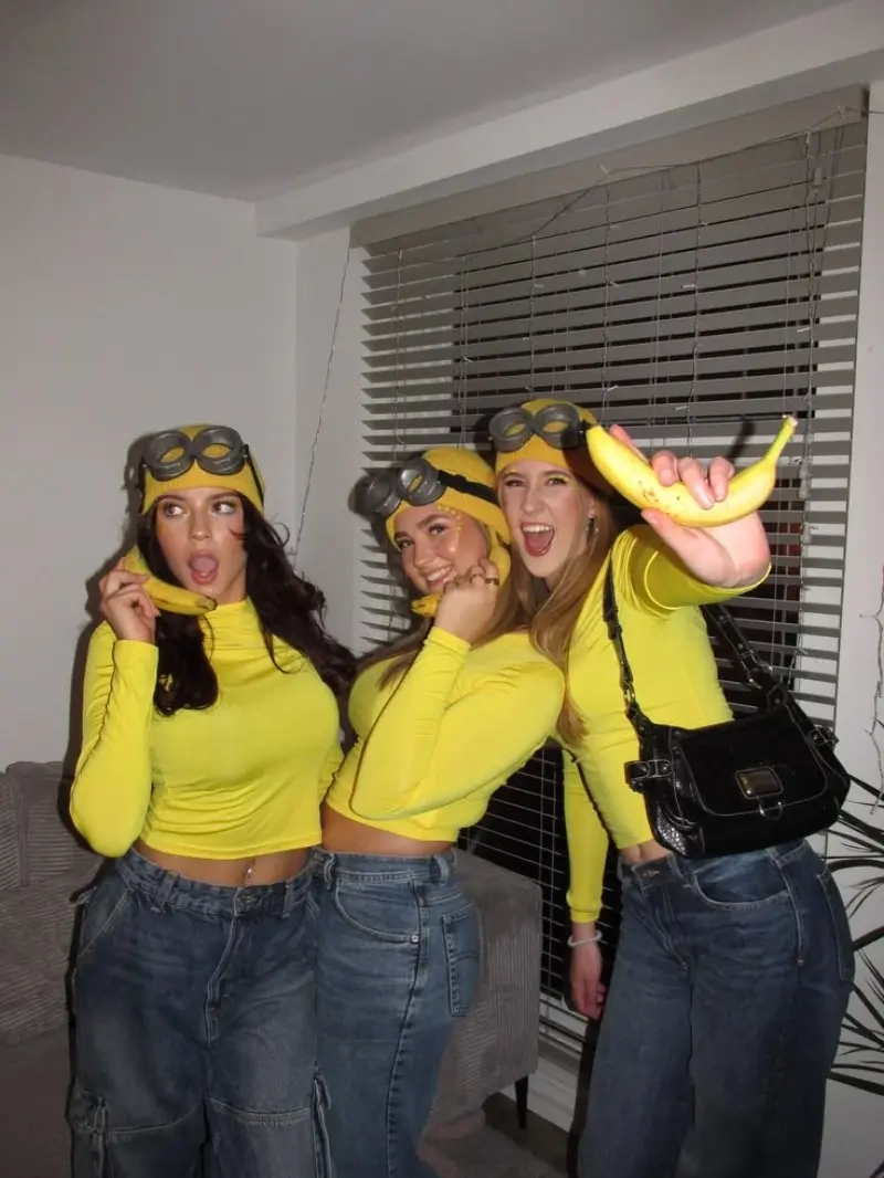 three women in yellow minions costumes with goggles and overalls holding bananas outfit 12