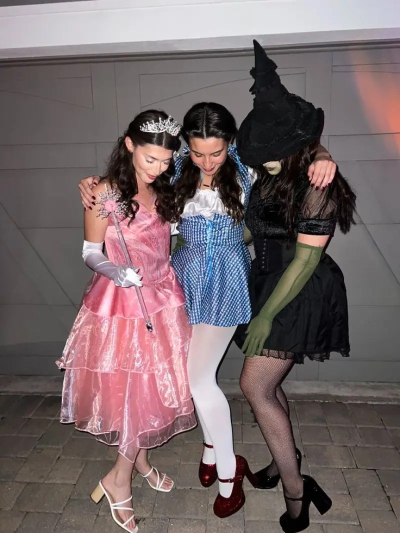 three women in wizard of oz costumes pink gown blue dress black witch outfit 1