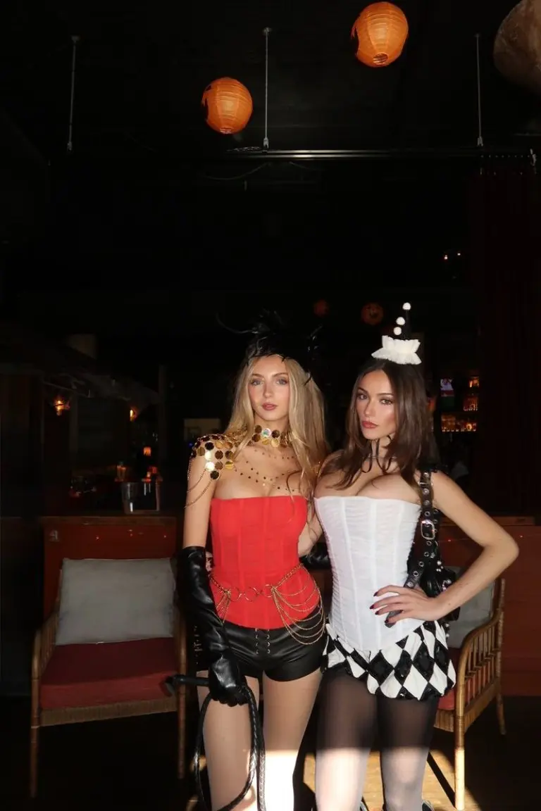 two women in contrasting red studded and white ruffled clown costumes with face paint 9