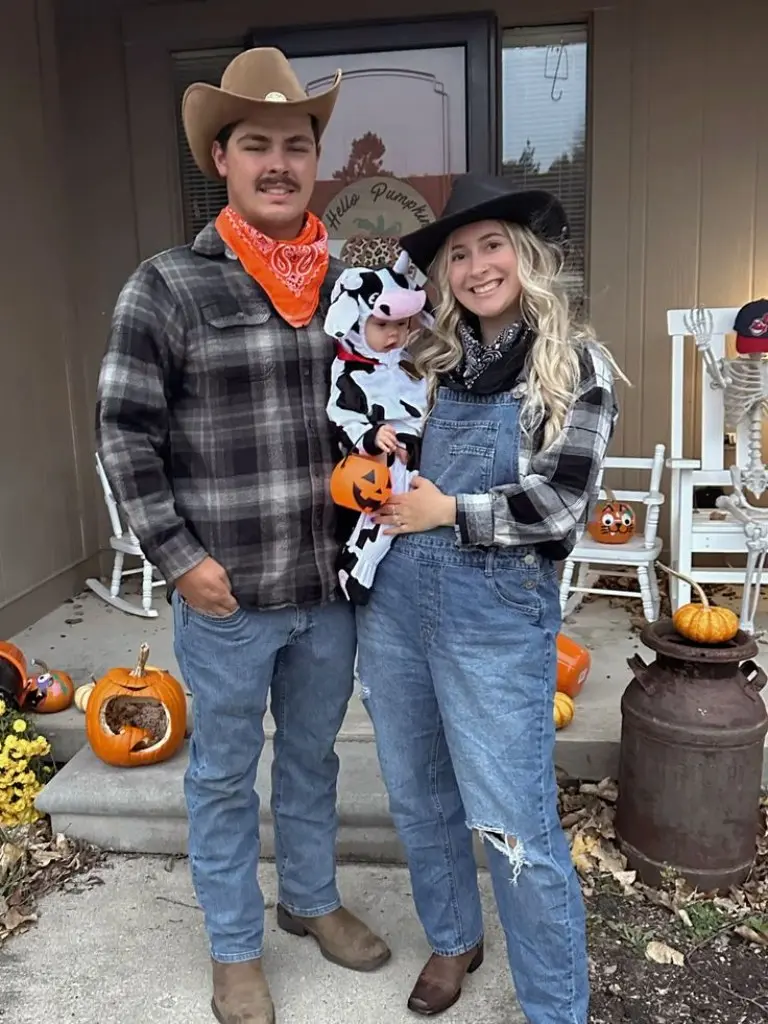 family in western themed halloween costumes cowboy hat plaid shirt overalls baby in cow print costume 2