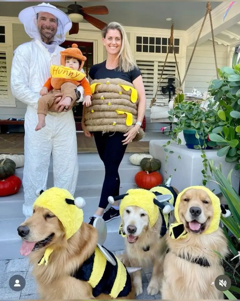 family dressed as beekeepers in white suits with baby in honey pot costume three dogs wearing bee costumes 7