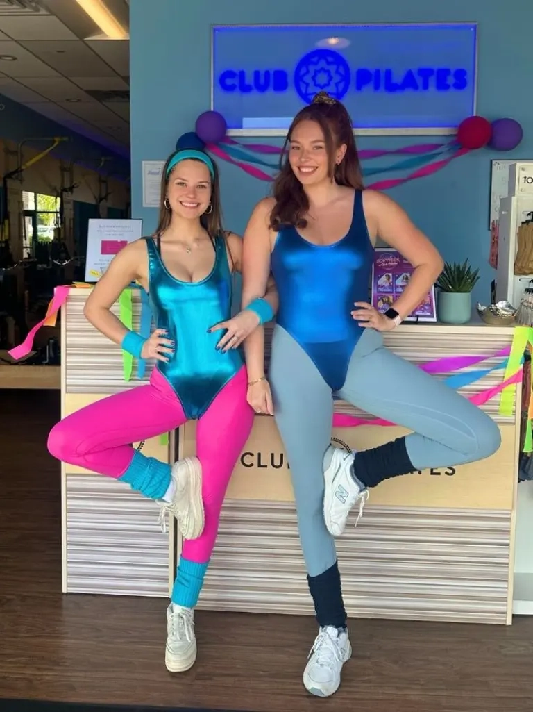 two women blue unitards teal pink accents leg warmers white sneakers club setting costume 9