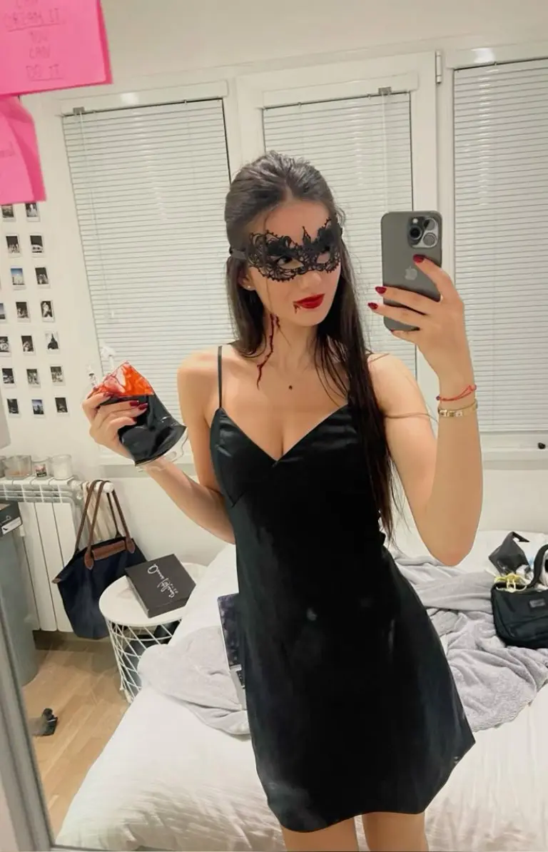woman in black slip dress with lace eye mask taking mirror selfie outfit 2