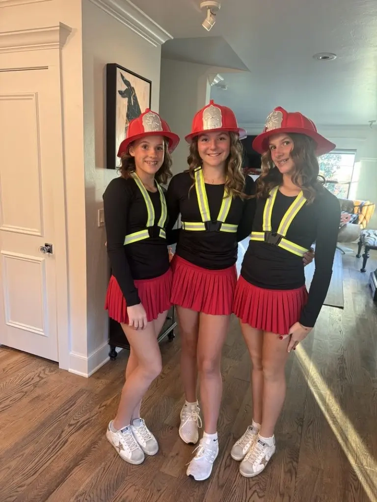 three teenage girls wearing firefighter costumes with red helmets yellow reflective stripes black tops red skirts outfit 3