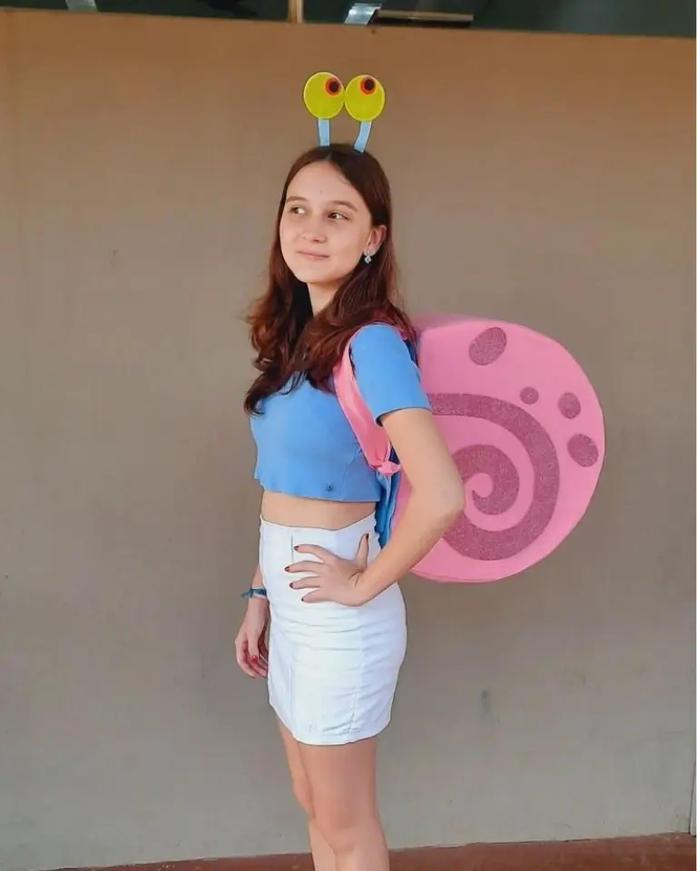 teenage girl wearing gary the snail costume with pink shell backpack antenna headband blue top white skirt outfit 10