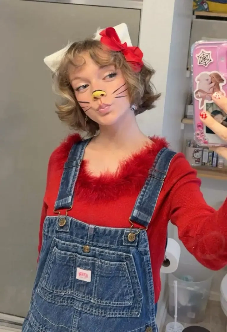 teenage girl wearing hello kitty costume denim overalls red fuzzy top white cat ears face paint outfit 13