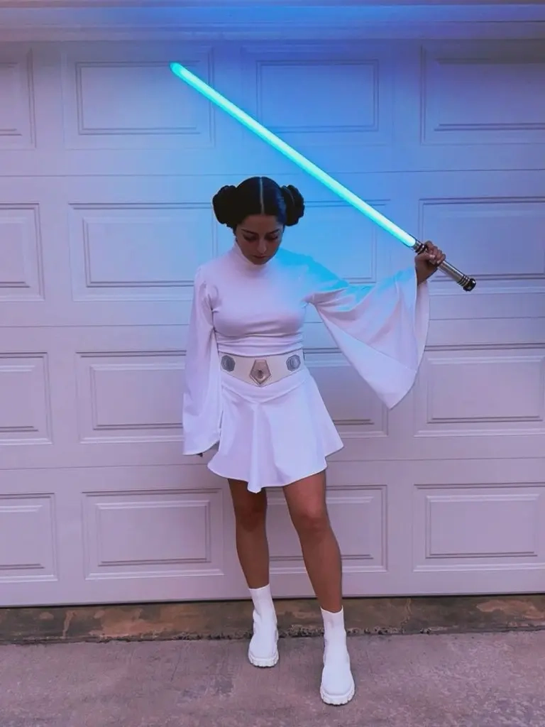 teenage girl wearing princess leia white costume with characteristic hair buns lightsaber outfit 8