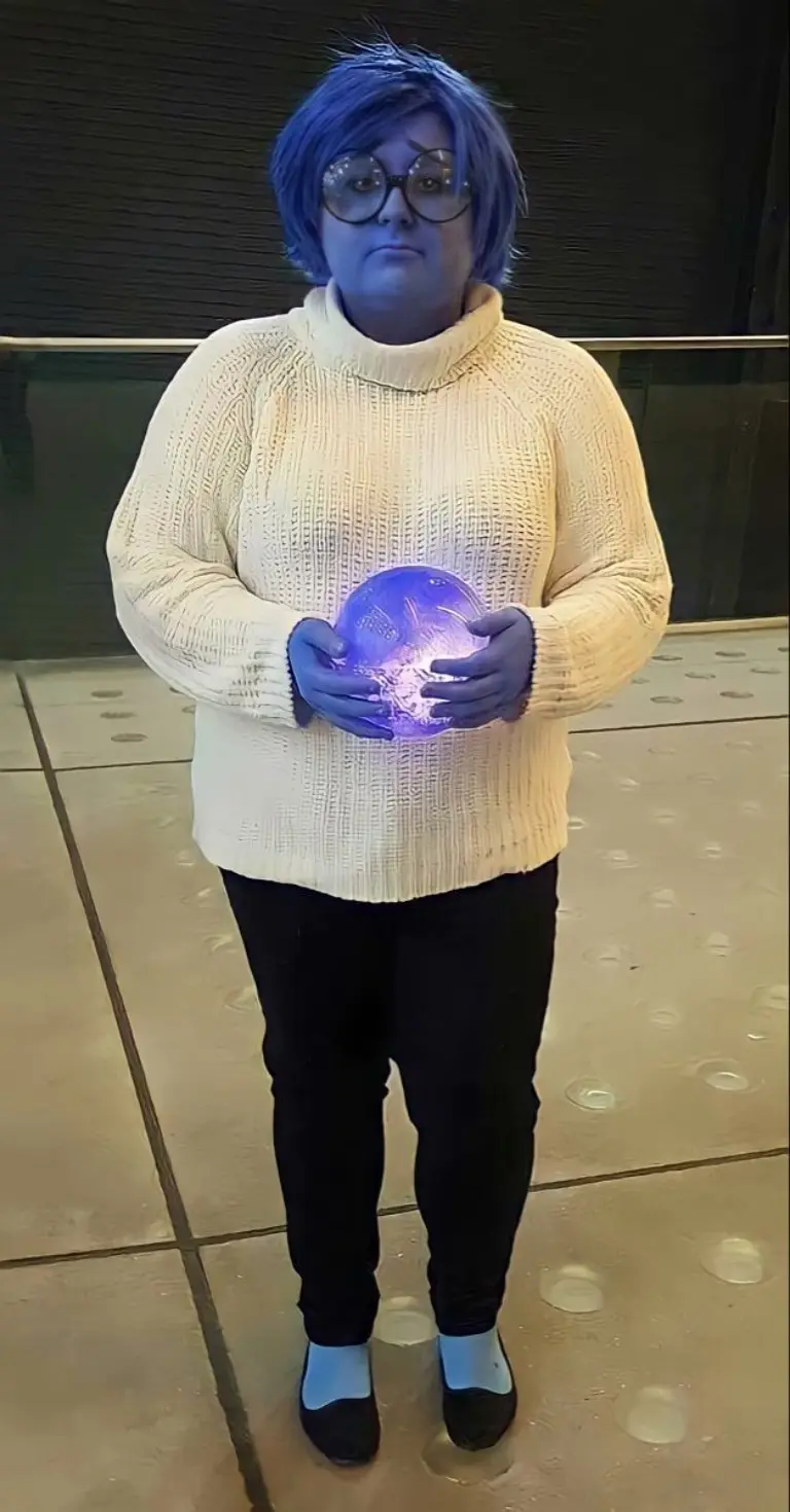 woman wearing yellow sweater blue wig and glasses holding glowing orb sadness costume outfit 13