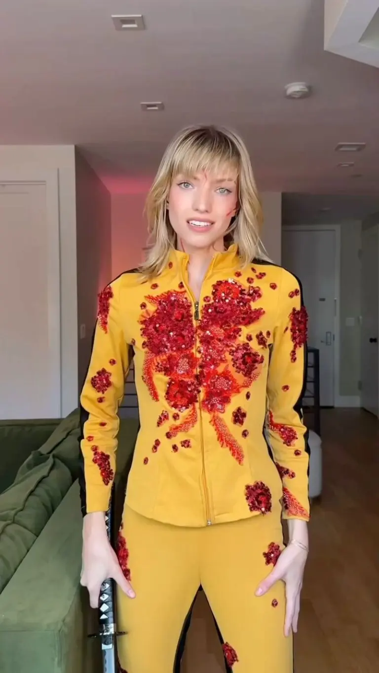 woman wearing yellow tracksuit with red details holding sword kill bill costume outfit 14