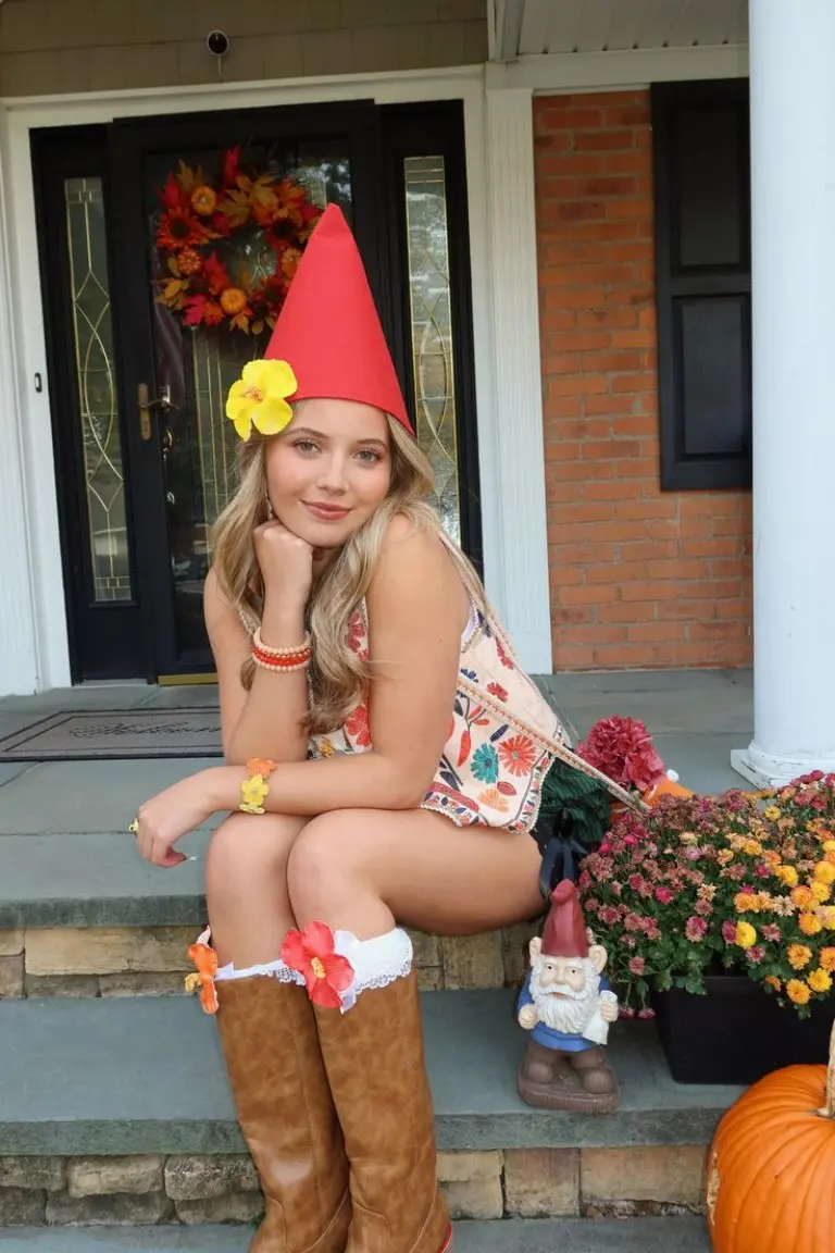 woman wearing floral dress with red pointed hat sitting outdoors garden gnome costume outfit 18