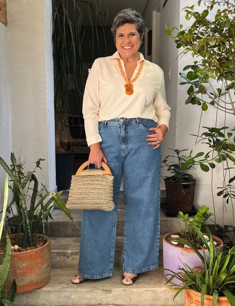 woman in cream polo top orange statement necklace wide leg jeans woven tote bag sandals 1