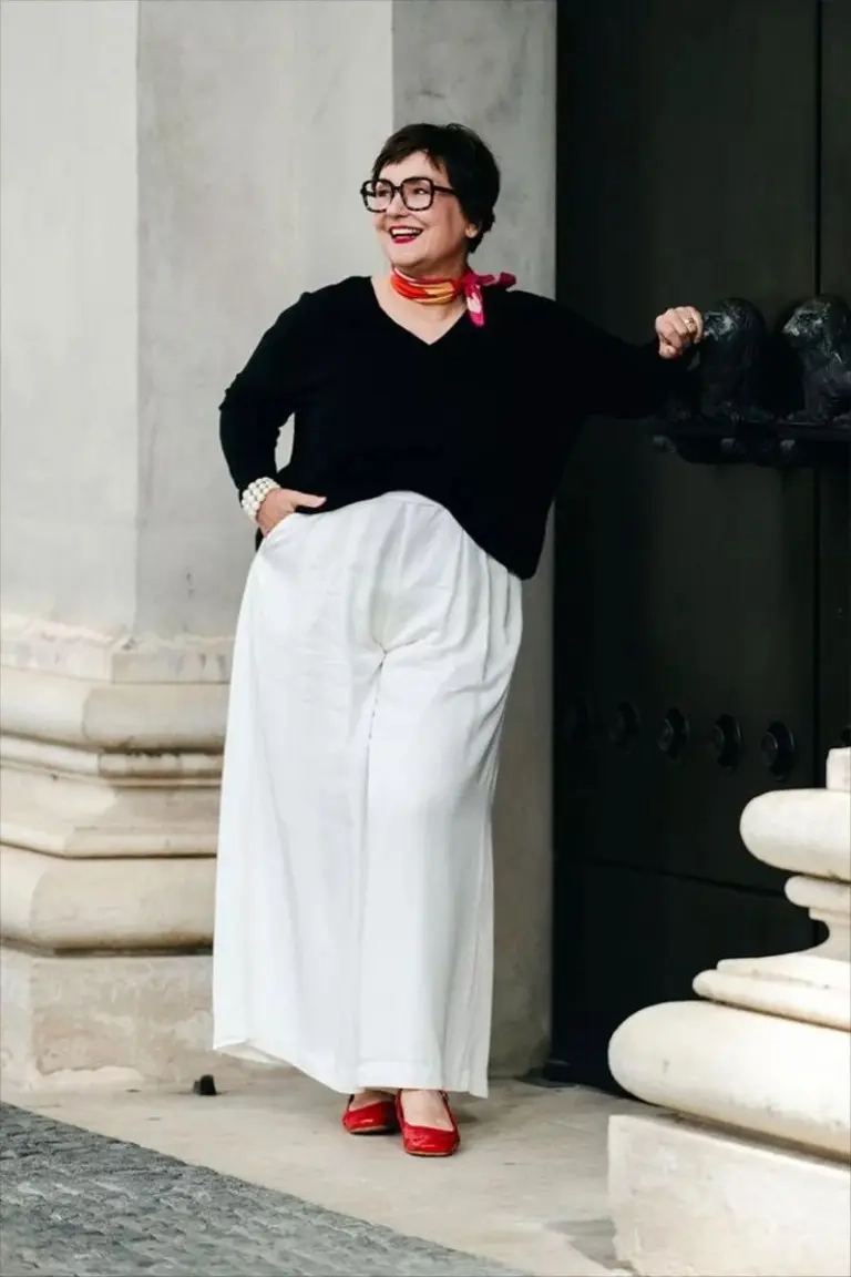 woman in black v-neck sweater white maxi skirt red scarf red flats statement glasses 7