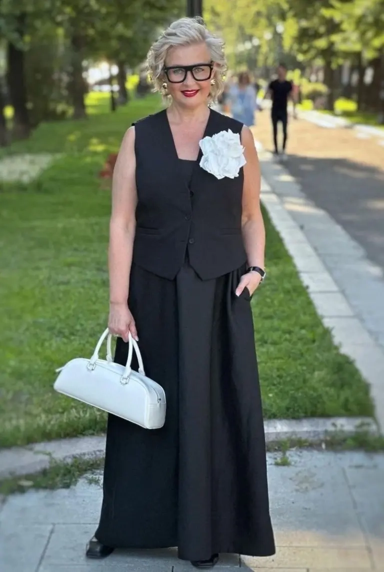 woman in black tailored vest white flower detail wide black pants white structured bag glasses 11