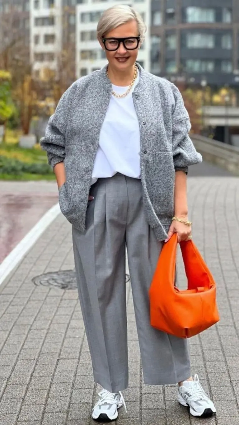 woman in grey oversized cardigan white top grey tailored pants chain necklace orange tote bag sneakers 17