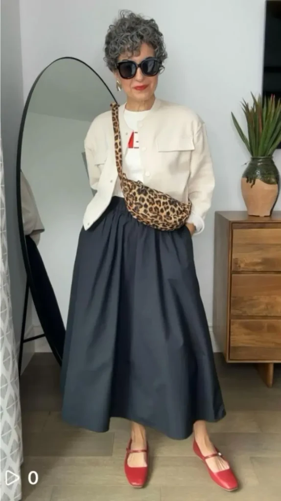 woman wearing cream sweatshirt with navy full skirt red mary jane shoes and leopard print belt bag outfit 12