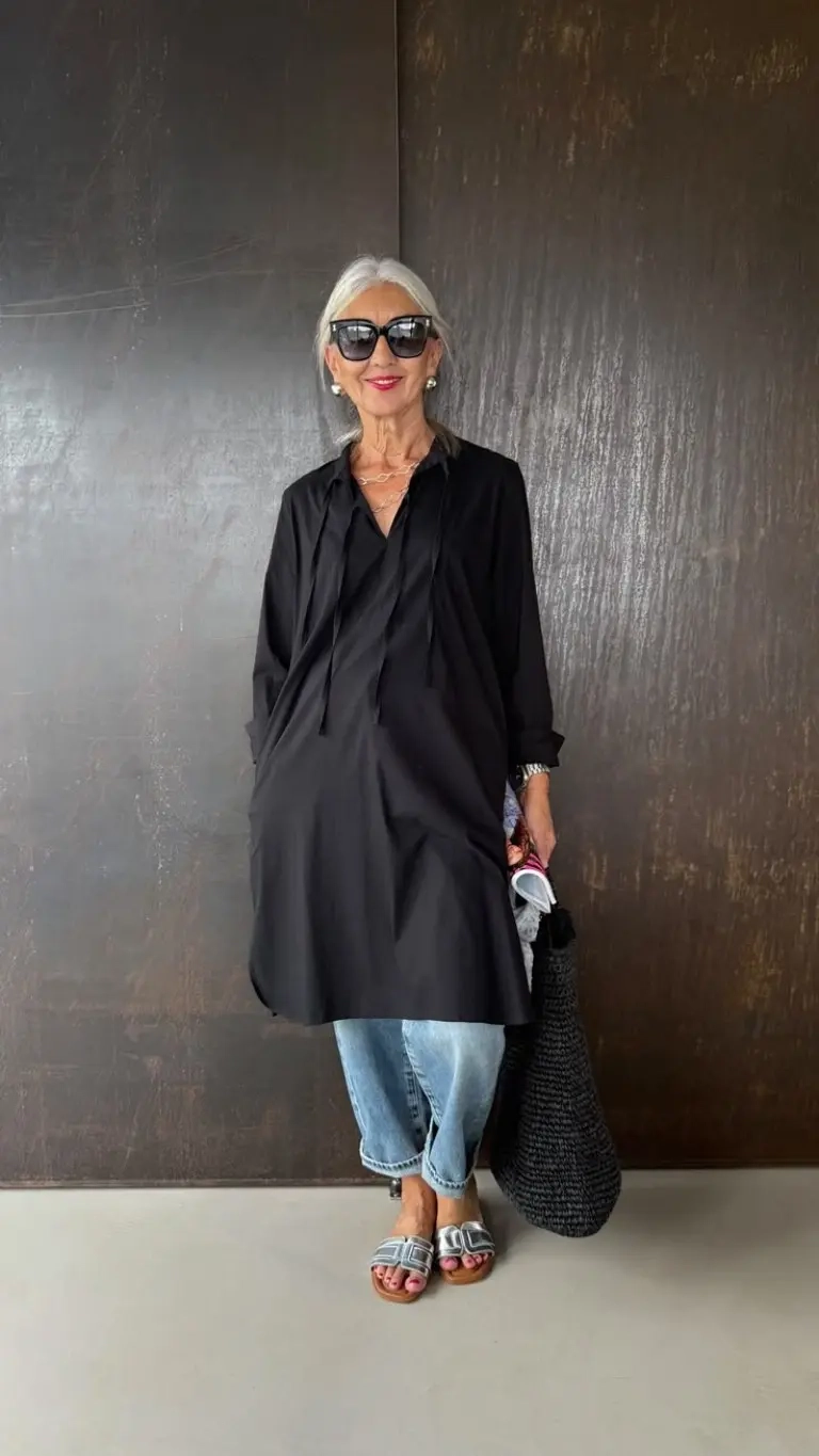 woman in oversized black shirt over cropped jeans with logo slides and woven bag outfit 8