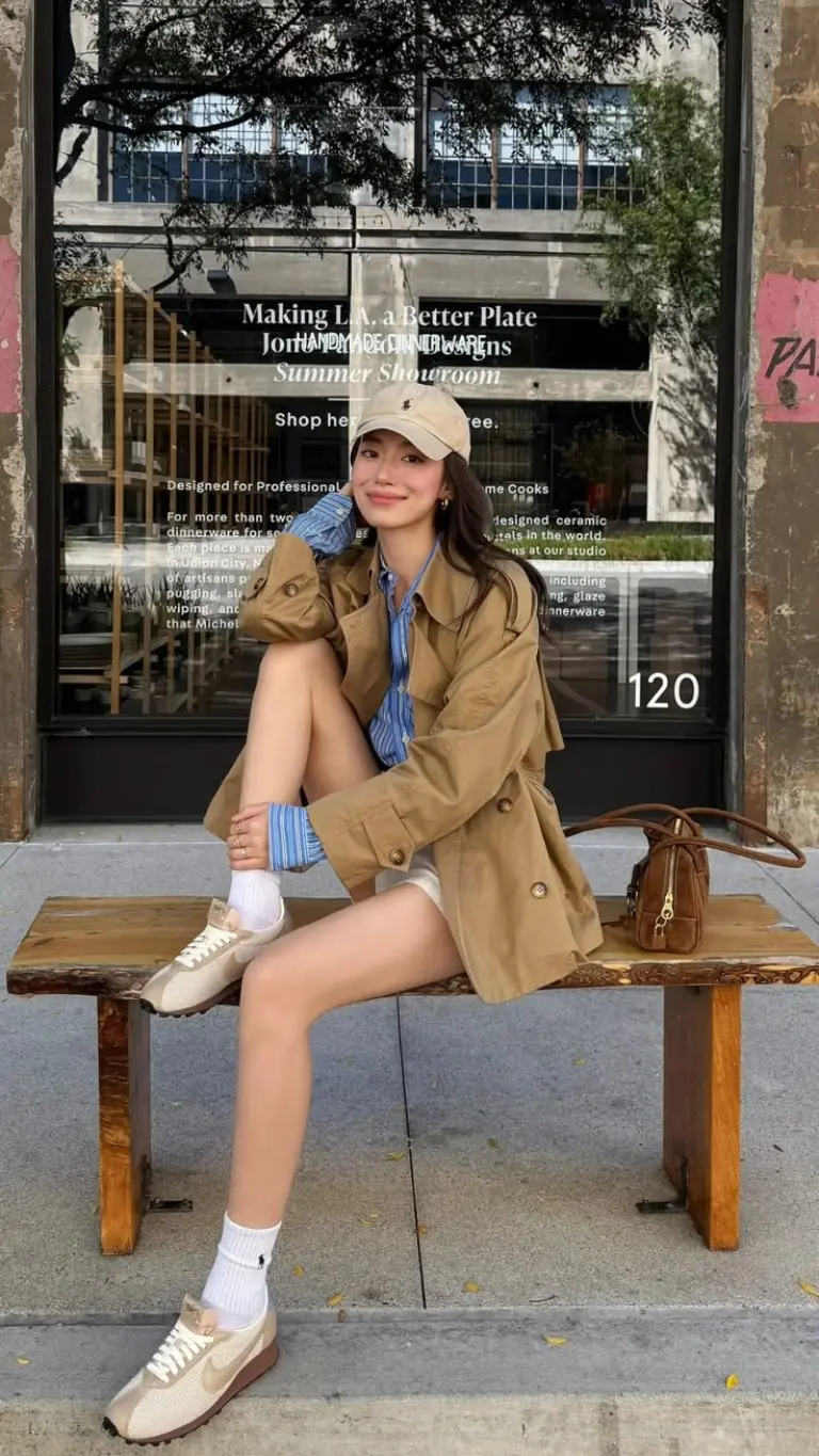 beige trench coat blue striped shirt baseball cap canvas sneakers outfit 18