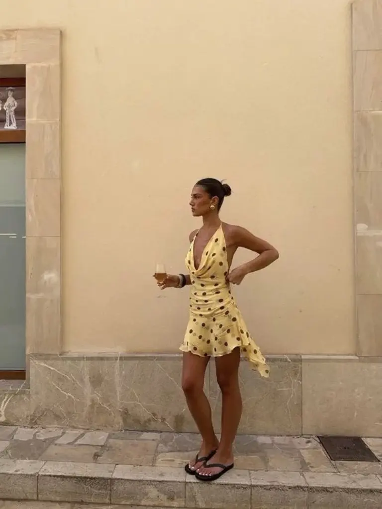 yellow polka dot wrap dress with black flip flops on stone street outfit 11