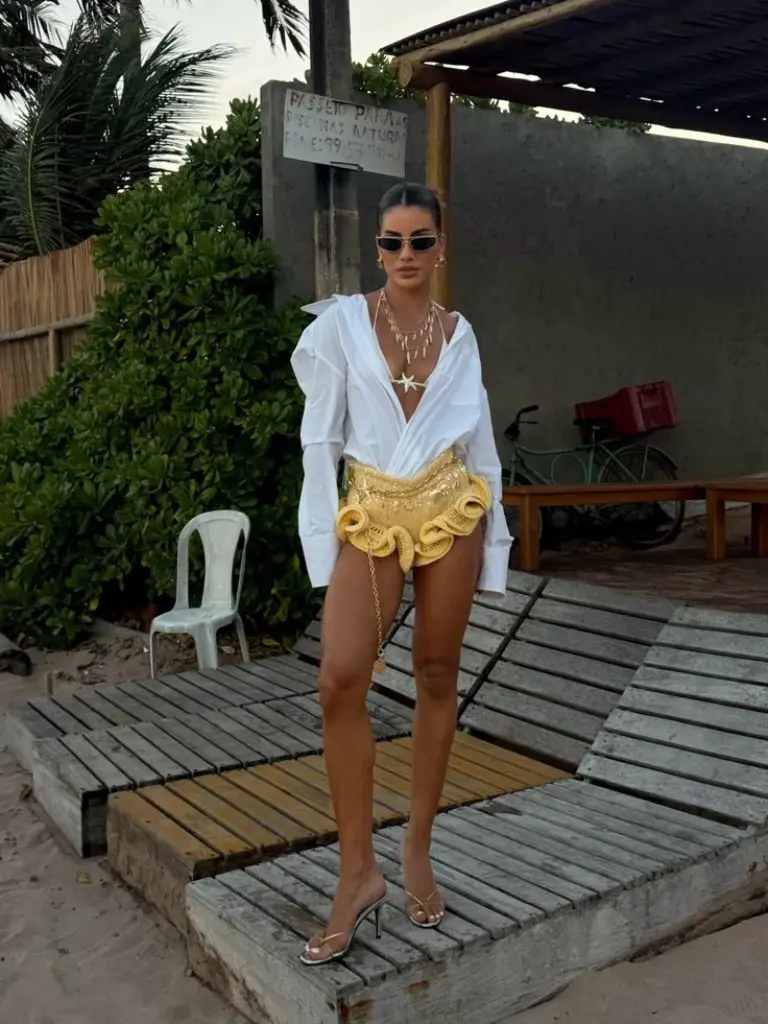 gold metallic bikini with white oversized shirt and layered necklaces holding champagne outfit 19
