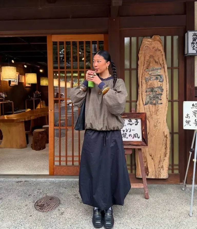 woman in black oversized cardigan navy midi skirt black oxford shoes crossbody bag traditional storefront outfit 8