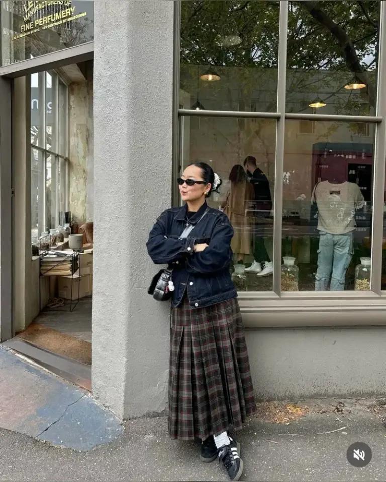 woman in black denim jacket brown plaid midi skirt black sneakers sunglasses traditional street outfit 9