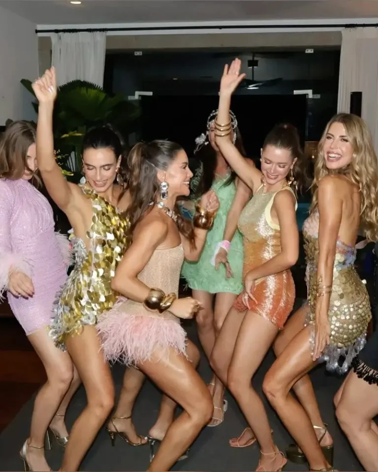 large group women wearing metallic dresses gold pink mint sequins feathers textures indoor party outfit 11