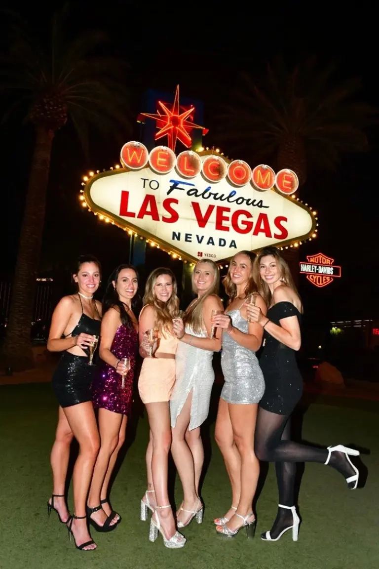 six women posing at vegas welcome sign wearing sequin mini dresses black burgundy silver colors outfit 5