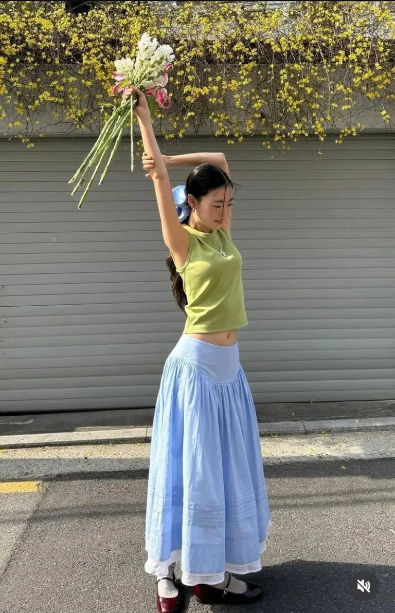 lime green crop top light blue tiered maxi skirt brown slip on loafers holding flowers outfit 2
