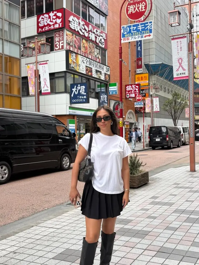 white oversized t-shirt black pleated mini skirt black knee high boots black crossbody bag night market outfit 13