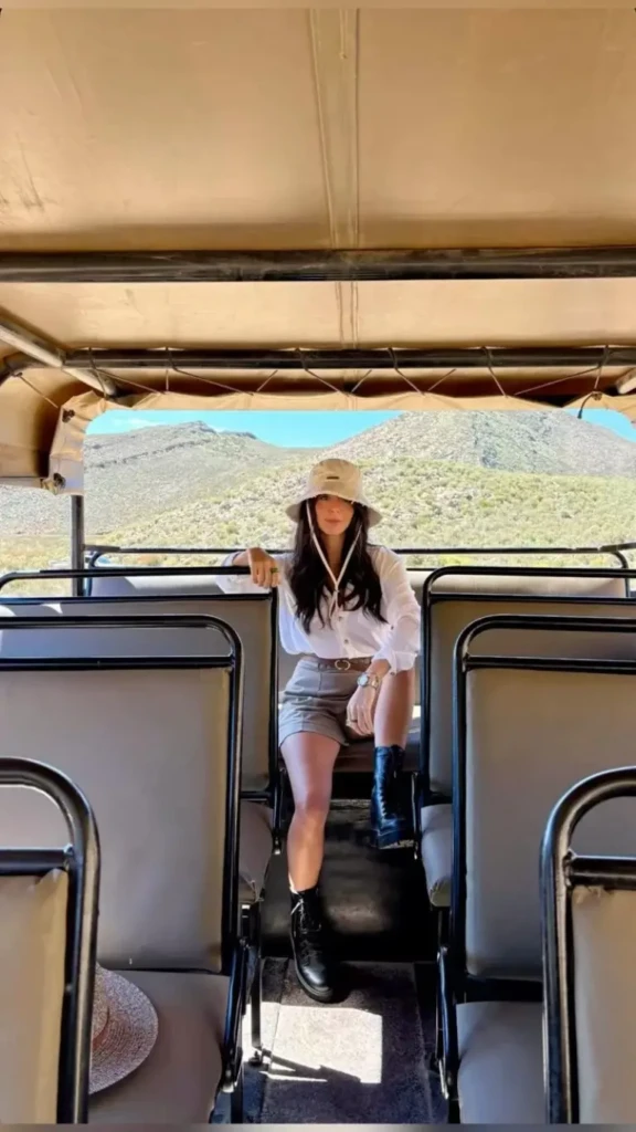 beige shirt dress brown cowboy hat sunglasses binoculars open safari vehicle landscape outfit 12