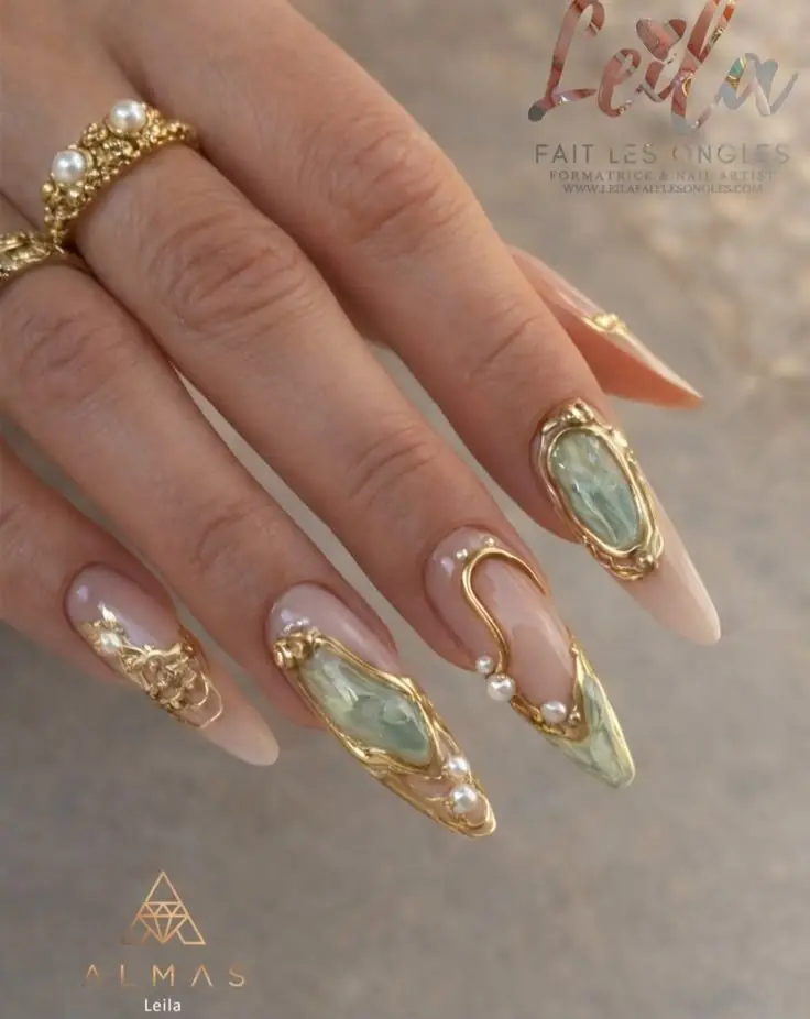 long stiletto nude blush nails with antique gold bezel frames sage green resin stones pearl accents and gold arch sculpts photo 3