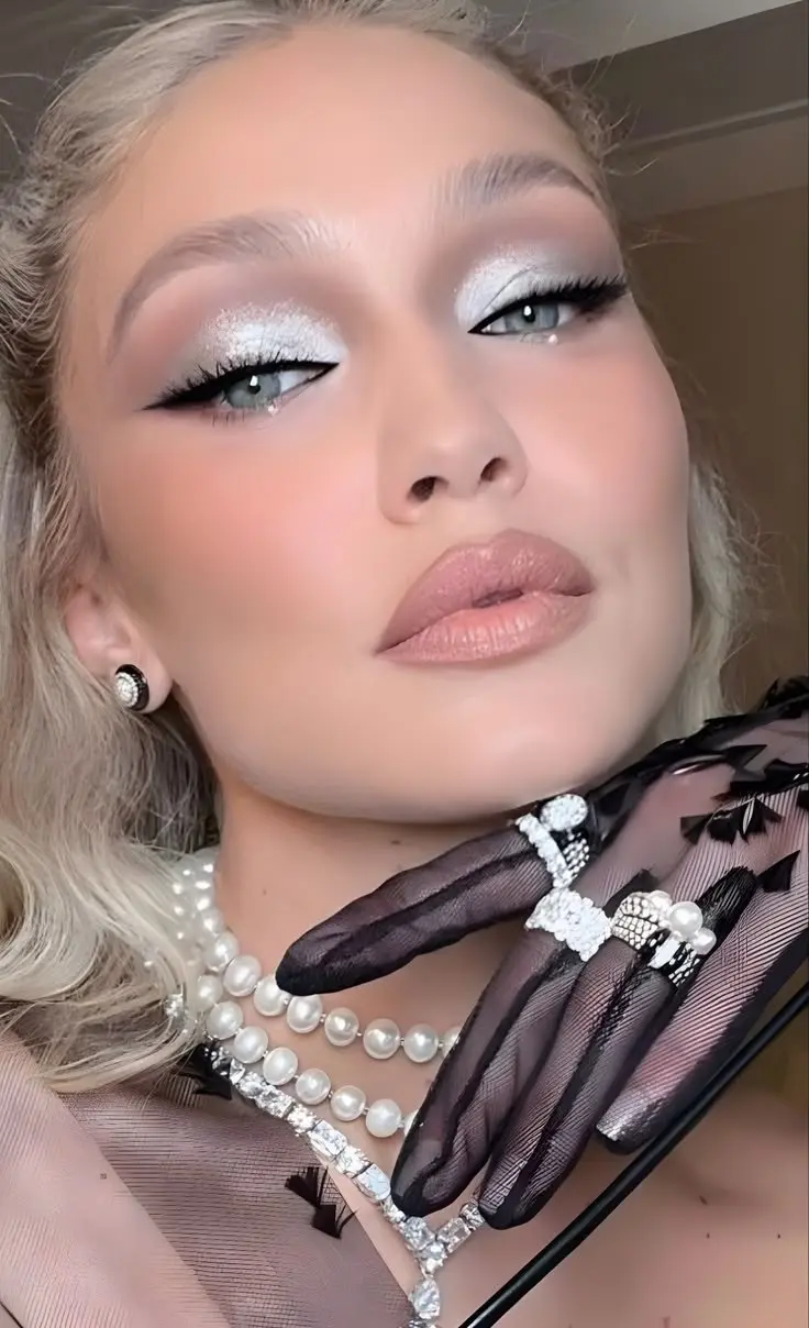 blonde woman with silver white packed eyeshadow graphic black liner wing rhinestone inner corner pearl skin nude pink lip cold girl makeup look 6