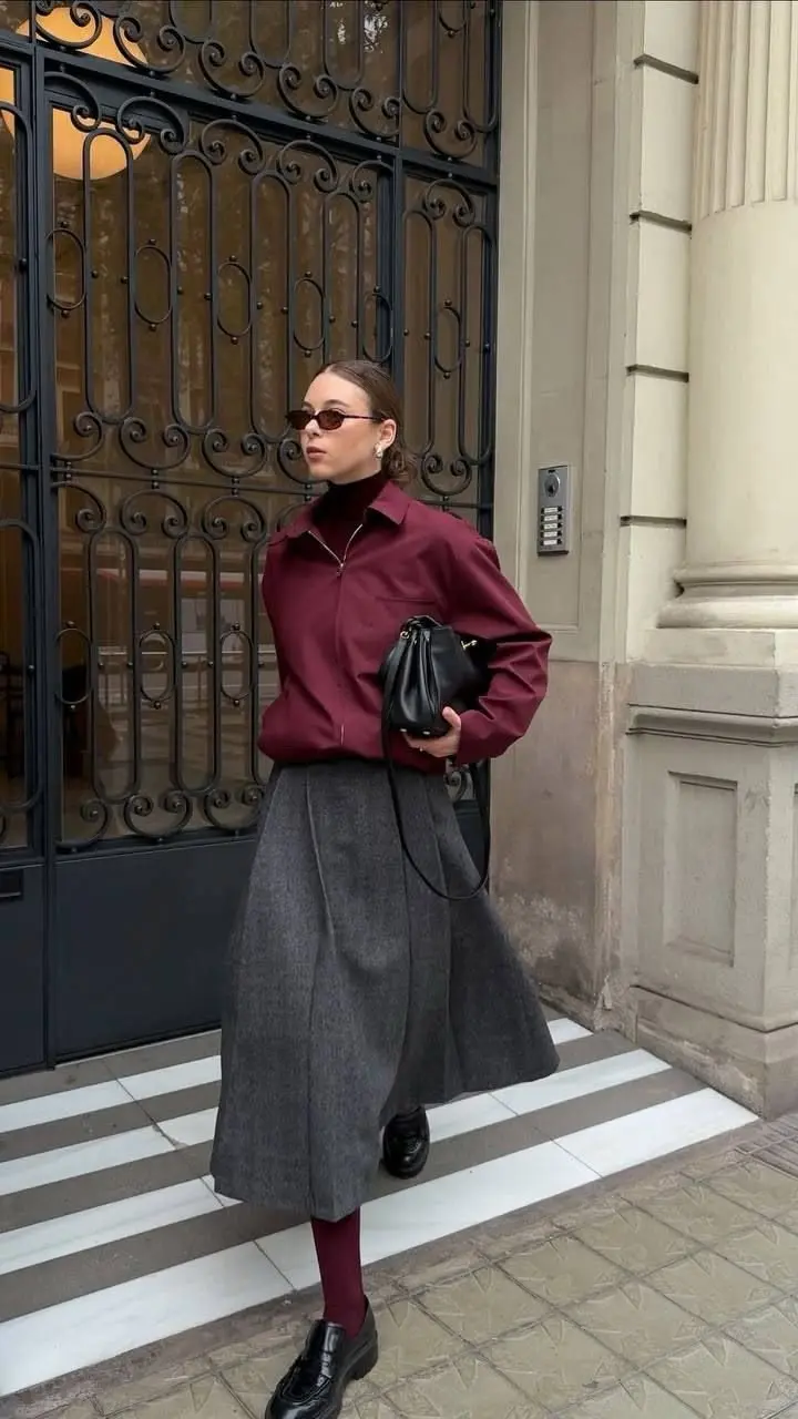 woman in burgundy zip jacket burgundy turtleneck grey pleated midi skirt matching burgundy tights black chunky loafers small black bag sunglasses fall work outfit 5