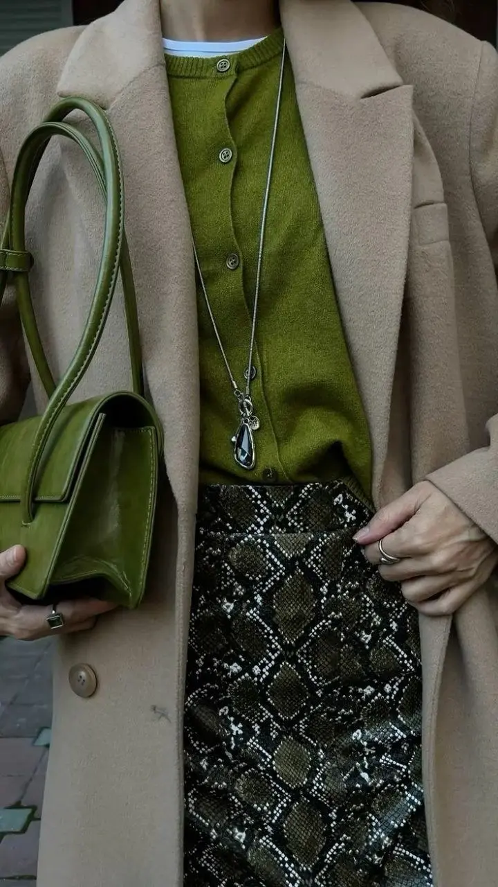 woman camel oversized coat olive green button cardigan white tee visible snake print midi skirt olive green structured top-handle bag silver pendant necklace fall work outfit 9
