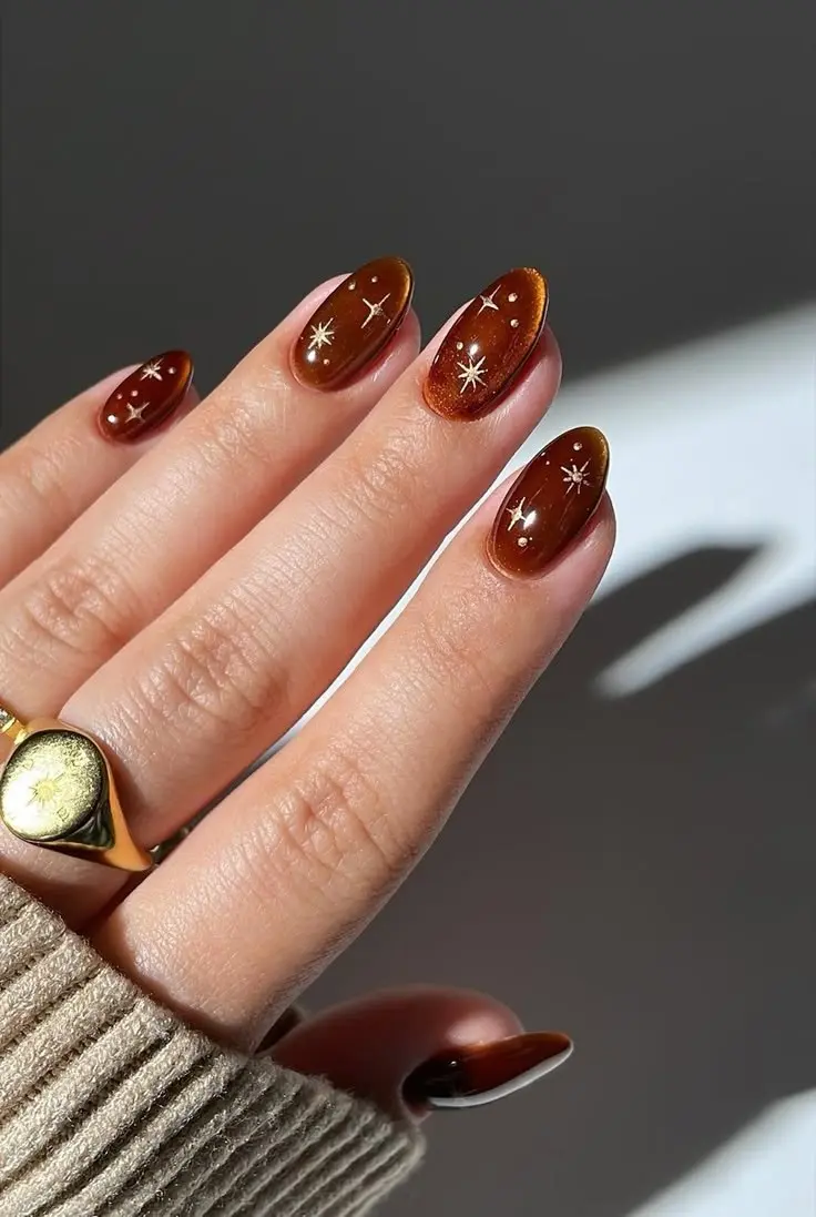medium short oval nails burnt amber jelly gel translucent base with scattered gold starbursts and crystal micro-dots photo 6